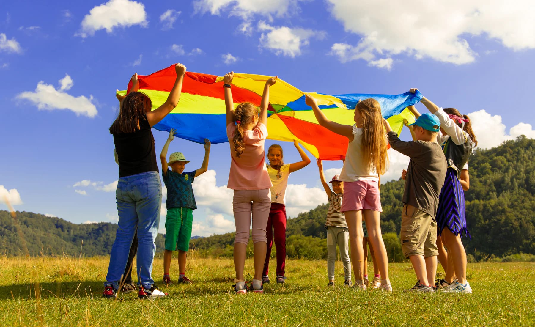 Children playing together with a colorful parachute outside